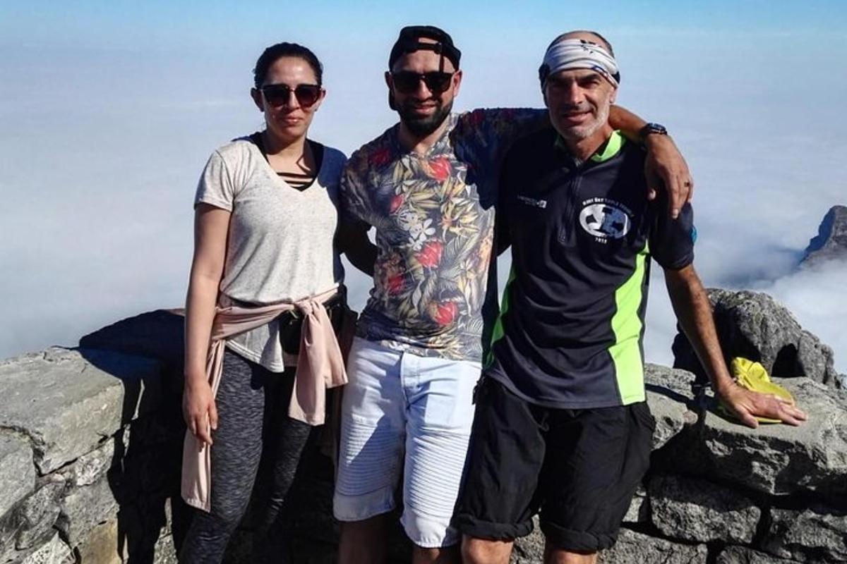 tre personer som står på toppen av et fjell