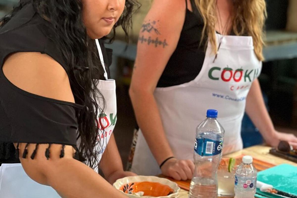 dalawang babae sa kusina na naghahanda ng pagkain na may mga bote ng tubig