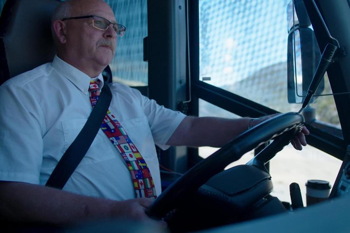 een man met een stropdas die een bus bestuurt