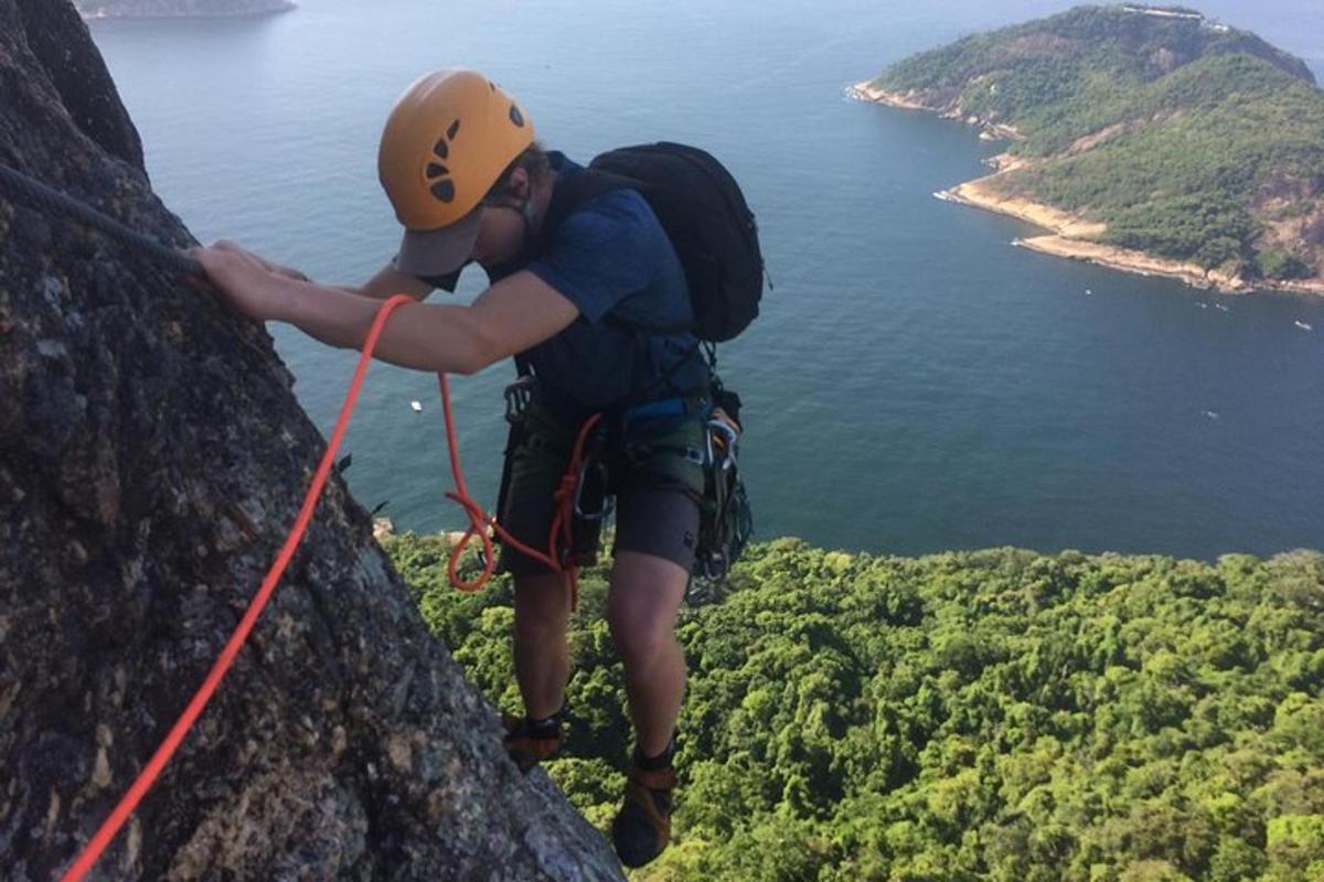 um homem está descendo de rapel de uma montanha