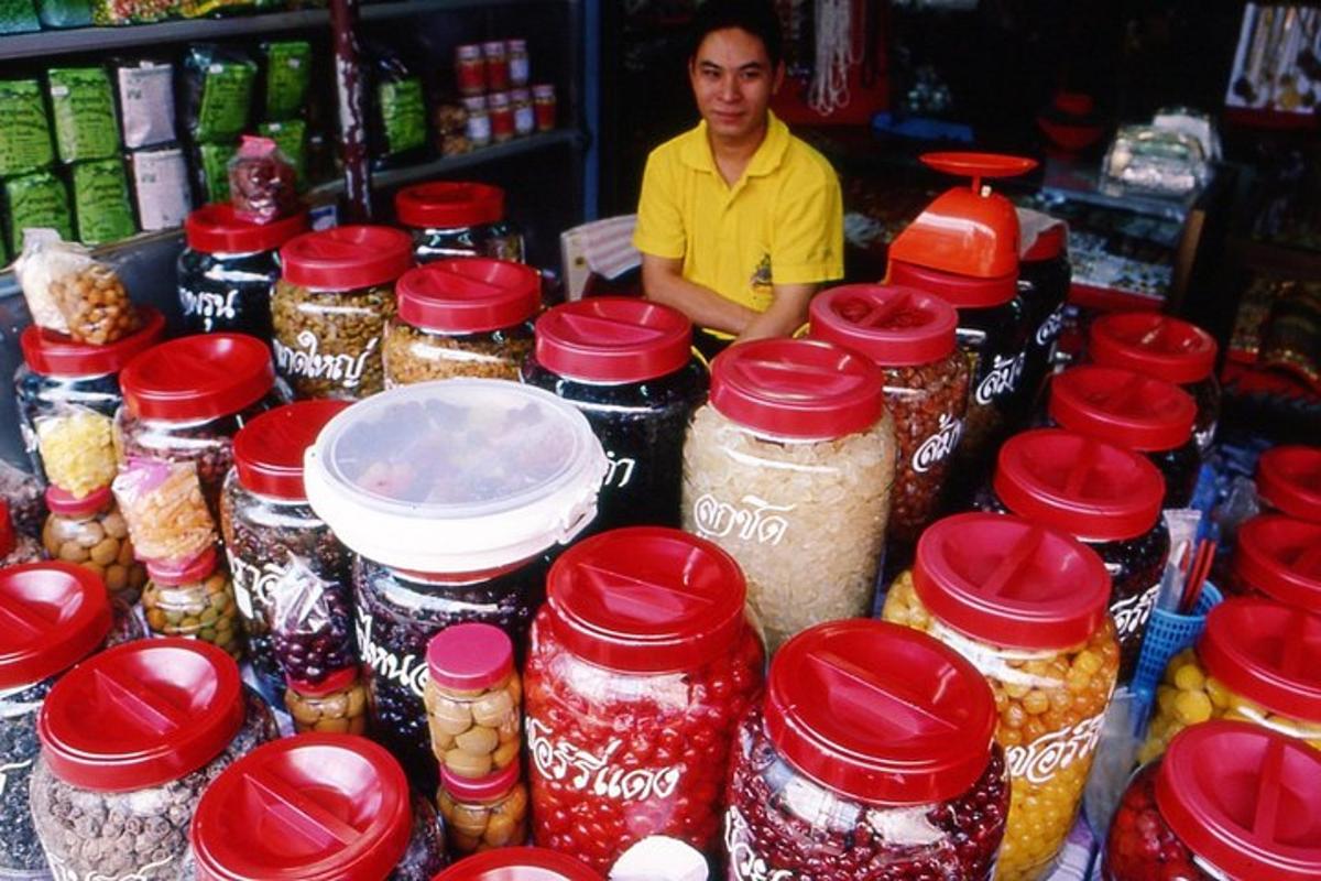 a man standing behind a counter with jars of food