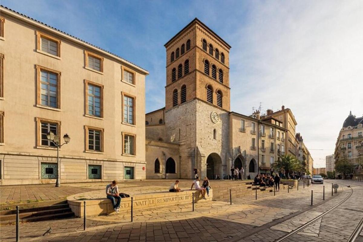 a building with a clock tower and people sitting in a courtyard
