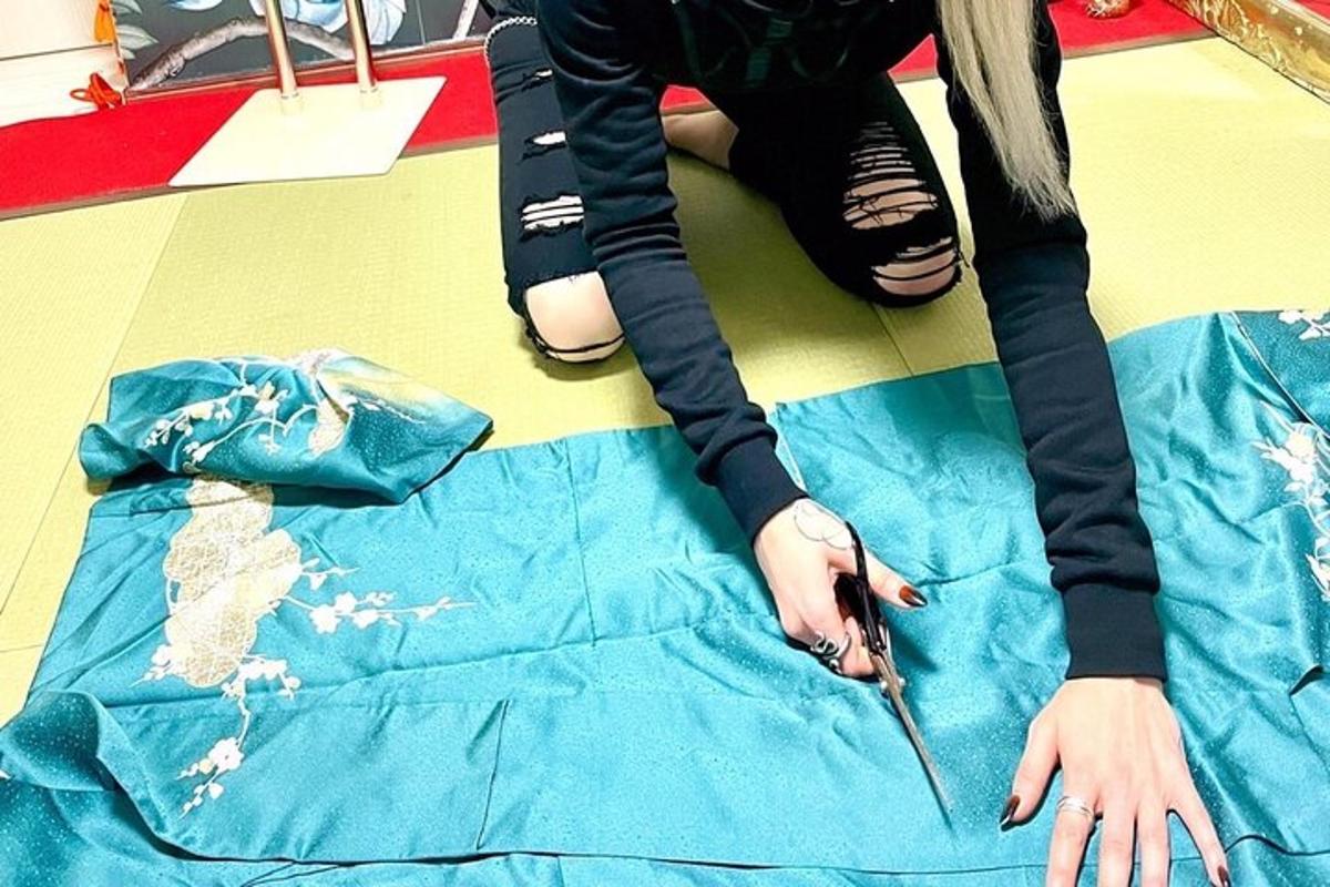 osoba sedící na podlaze a stříhající kus deky