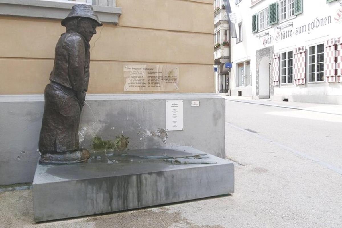 a statue of a boy sitting on top of a fountain