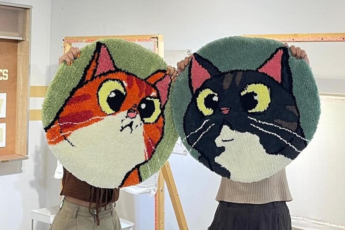 due persone che tengono in mano cuscini raffiguranti due gatti