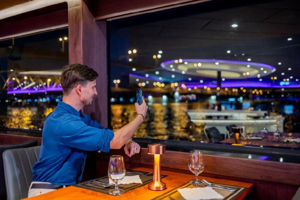 muž držící mobilní telefon u stolu v restauraci