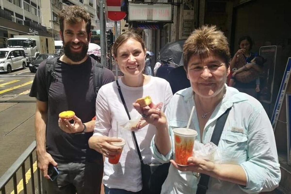 dve ženski in moški, ki držijo hrenovke in pijačo