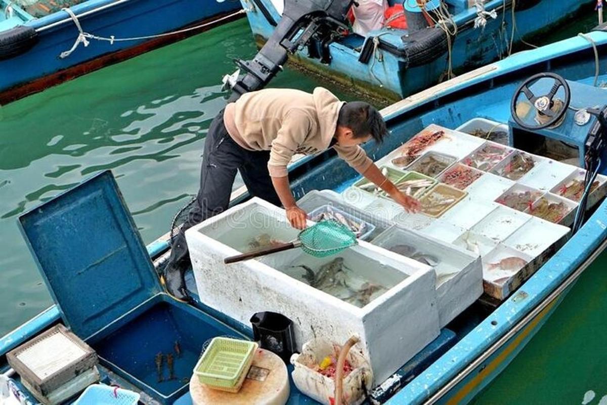 a man standing in a boat with a box of food