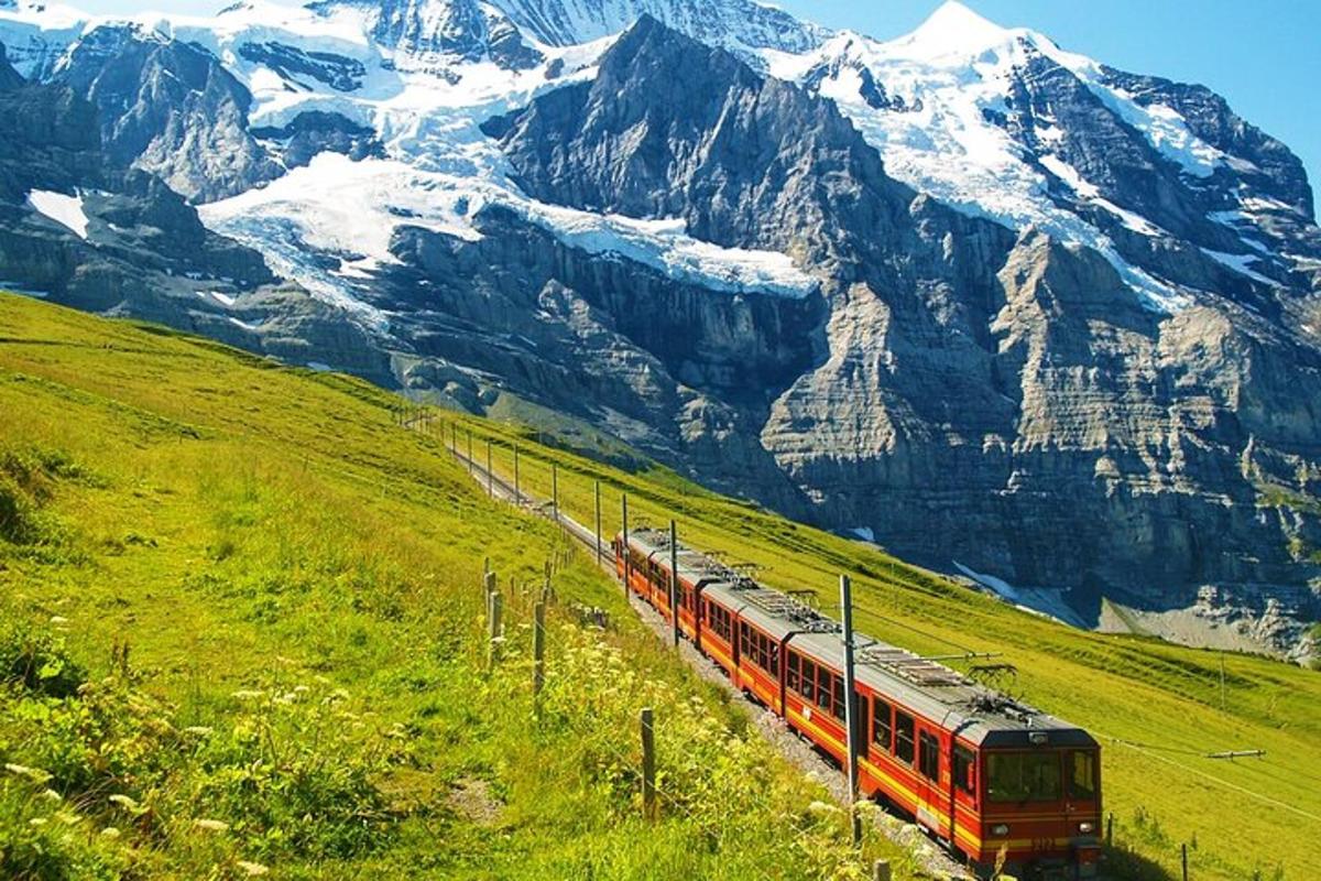 um trem descendo uma colina com montanhas ao fundo