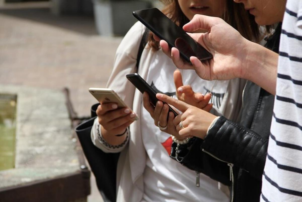 skupina ľudí pozerajúca sa na svoje mobilné telefóny