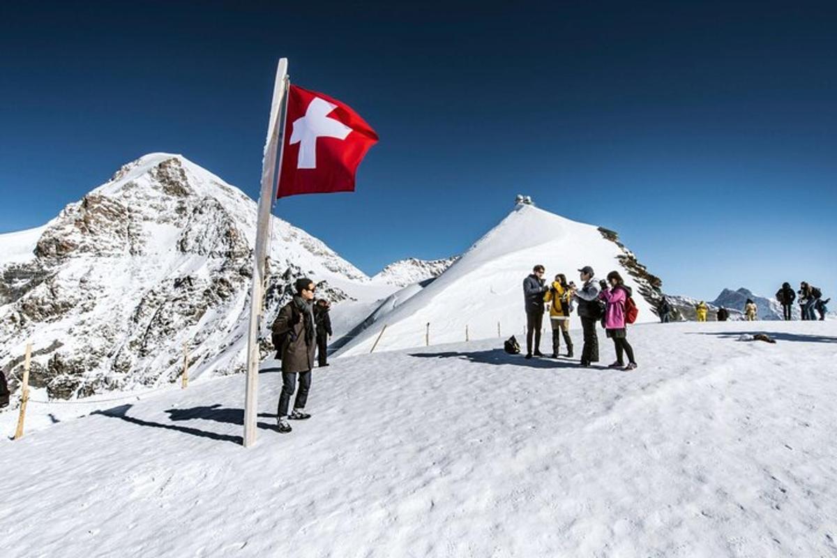 um grupo de pessoas em pé ao lado de uma bandeira em uma montanha