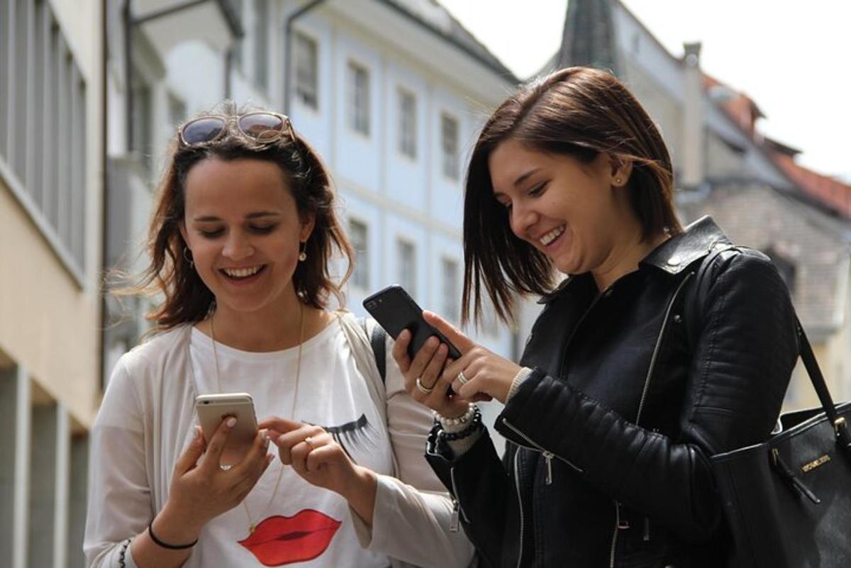 zwei Frauen lachen, während sie auf ihre Handys schauen
