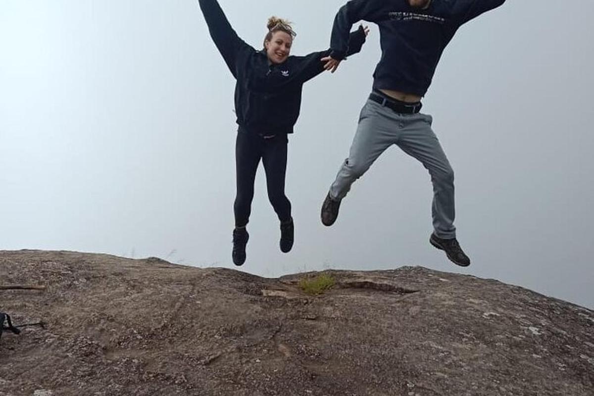 two men jumping in the air on top of a rock