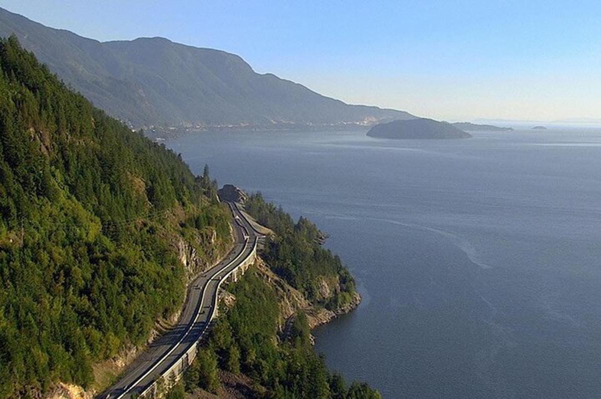 an aerial view of a road on a hill next to the water