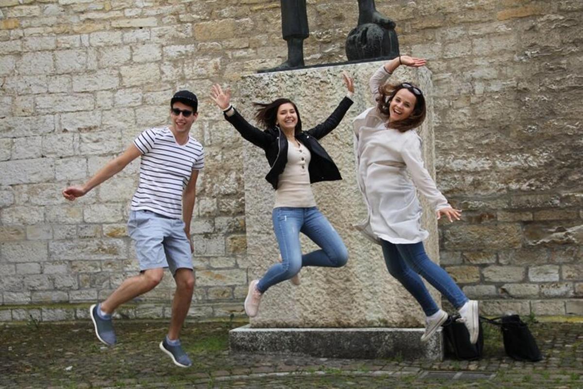tre persone che saltano davanti a un muro di pietra
