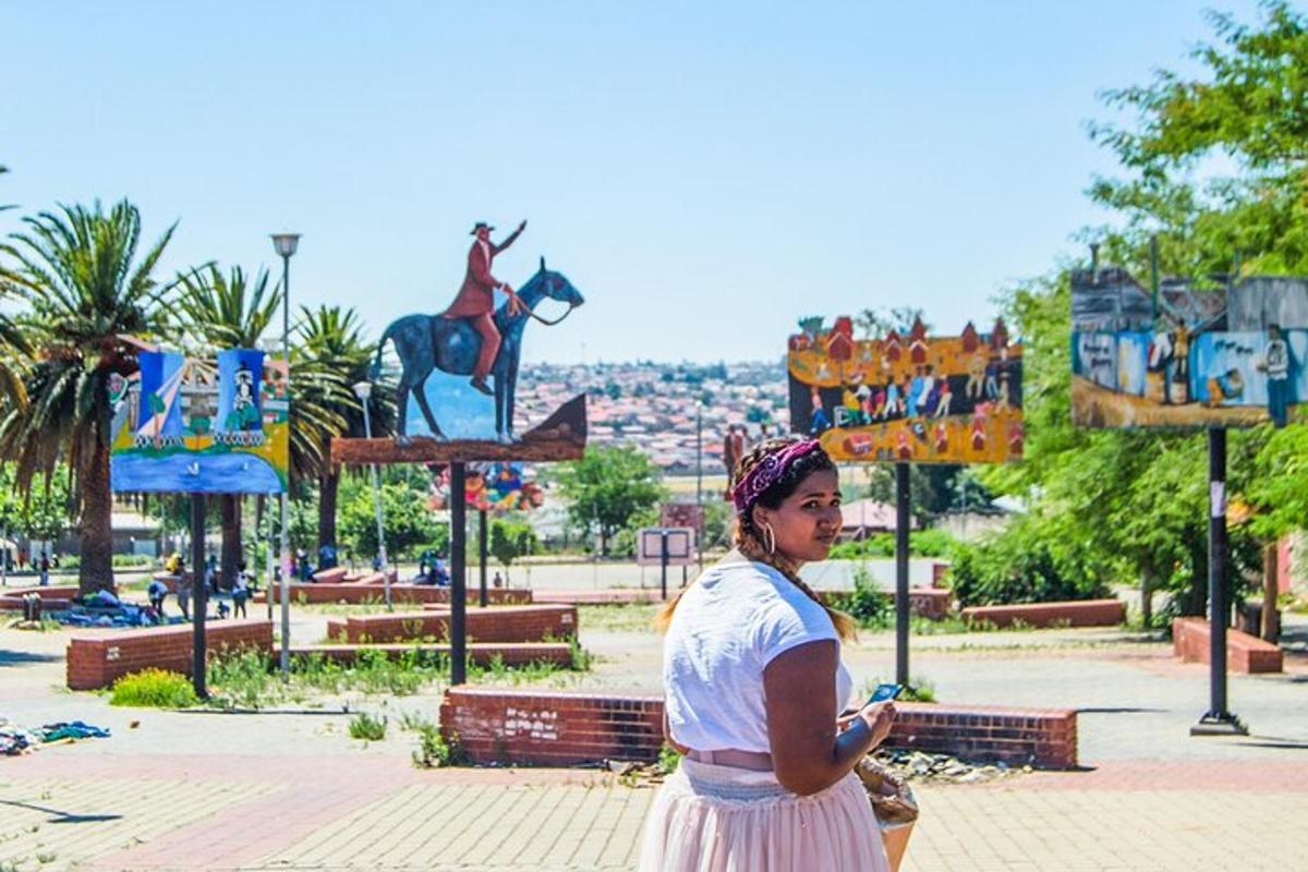 a woman standing in a park with a statue of a horse