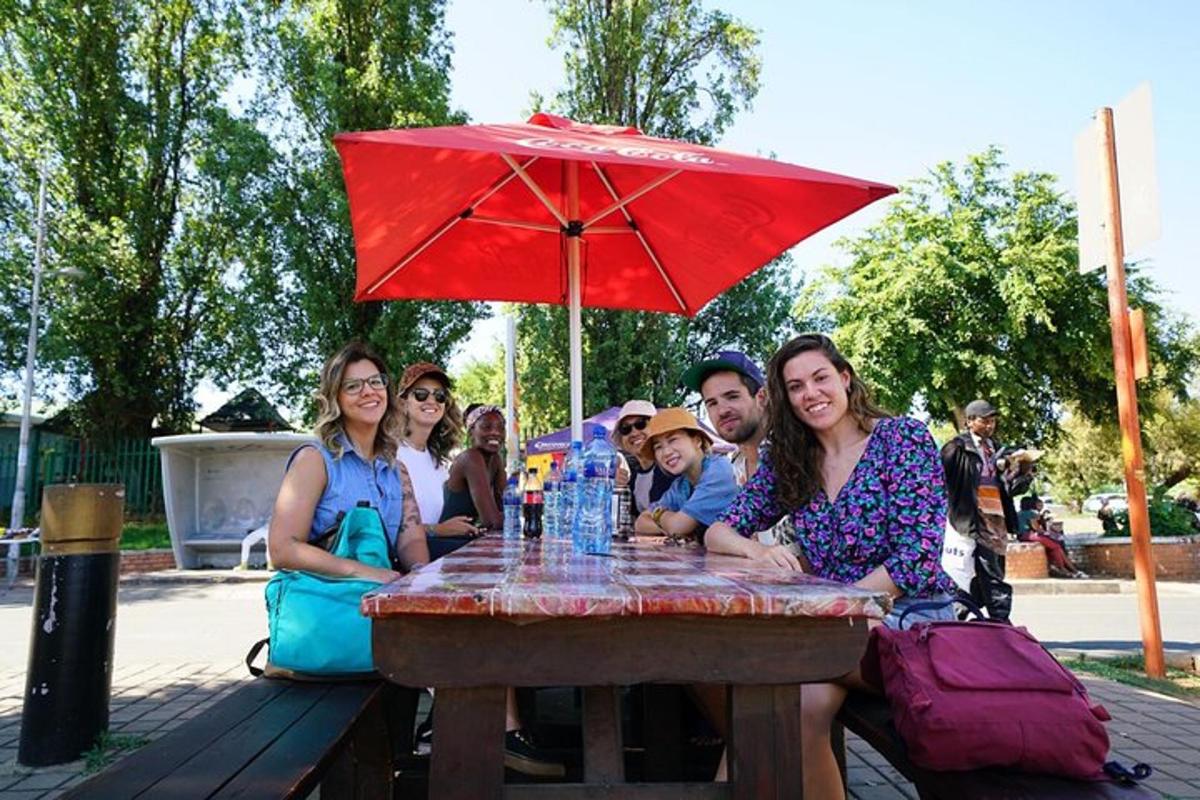 a group of people sitting at a picnic table with an umbrella