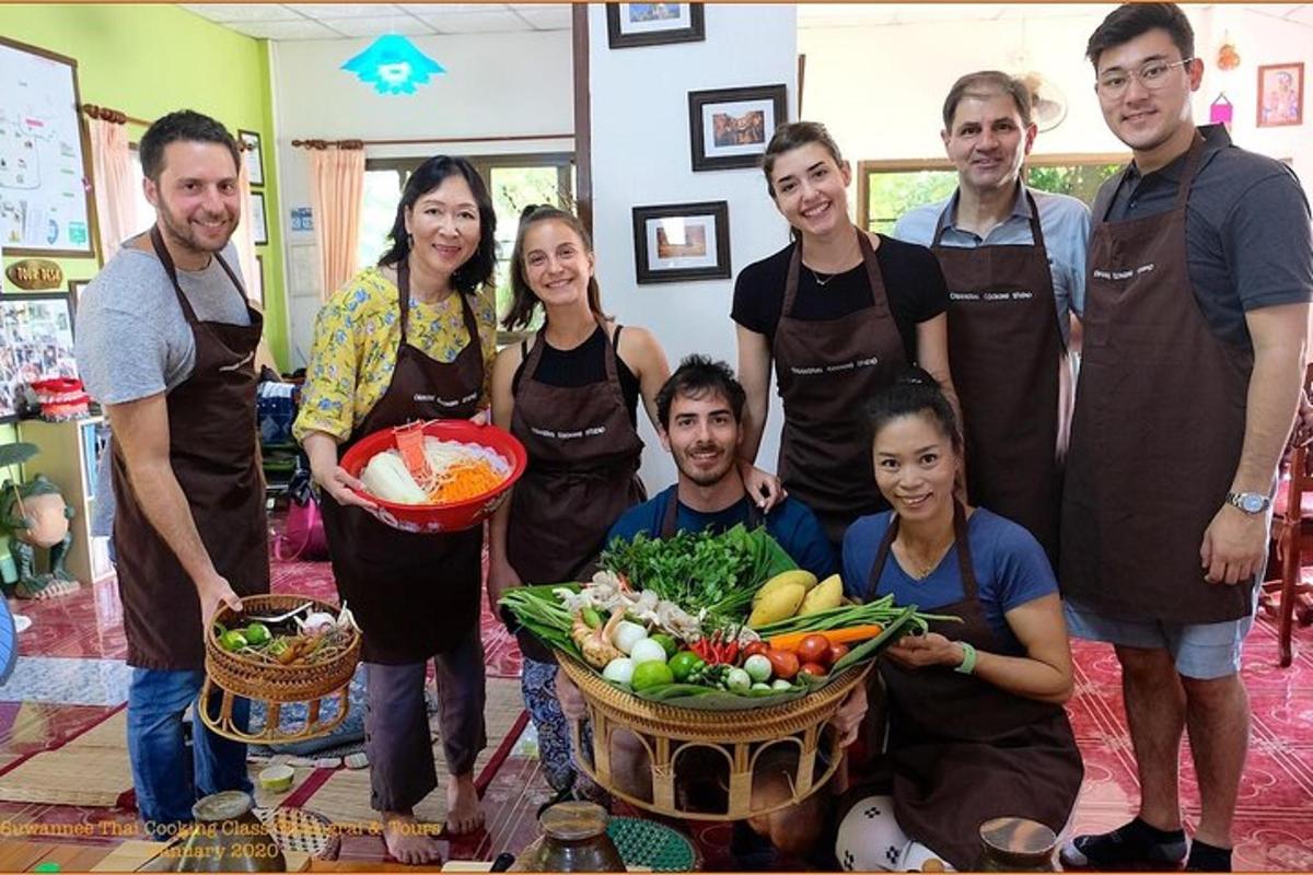 a group of people standing in a kitchen with a basket of vegetables