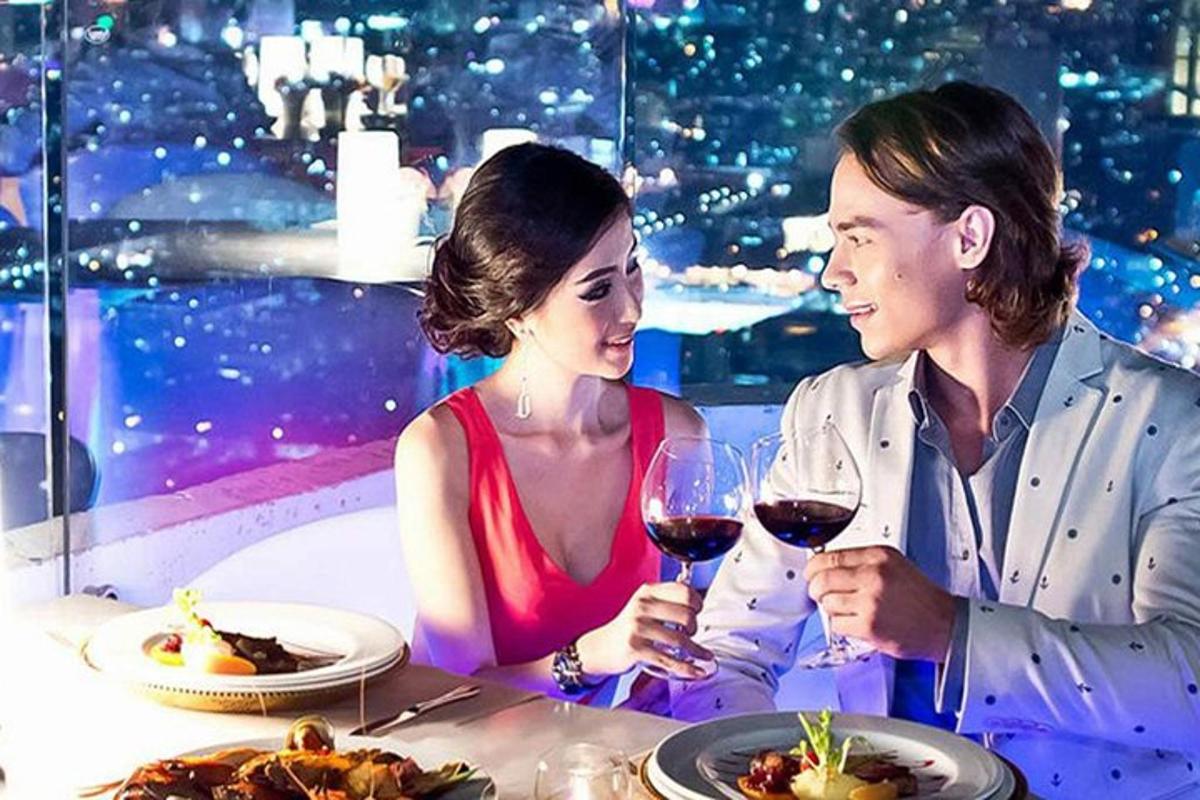 Un hombre y una mujer sentados en una mesa con copas de vino.