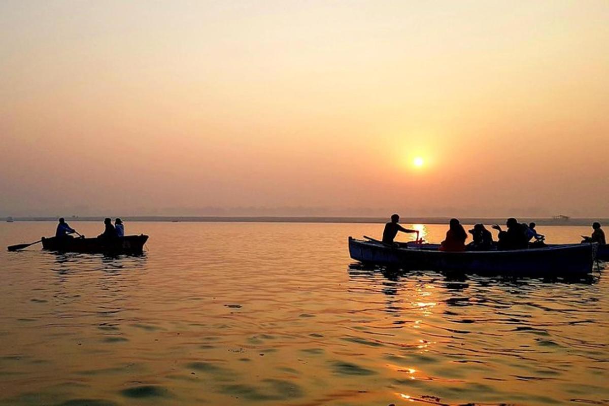un grup de persones en barques a l'aigua a la posta de sol