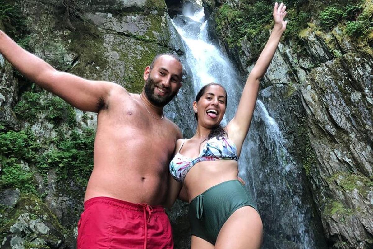 seorang lelaki dan seorang wanita berdiri di hadapan air terjun
