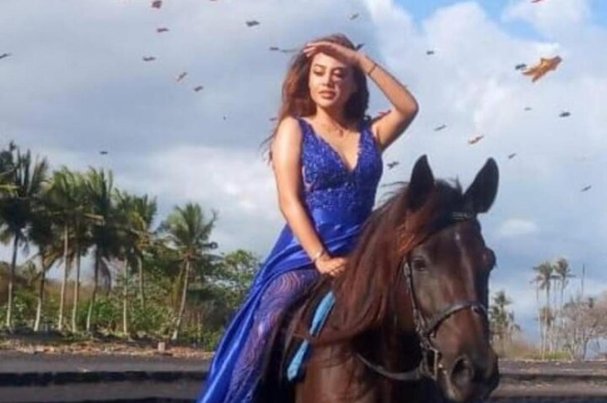 a woman in a blue dress riding a horse