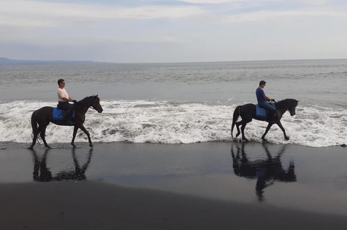 two people are riding horses on the beach