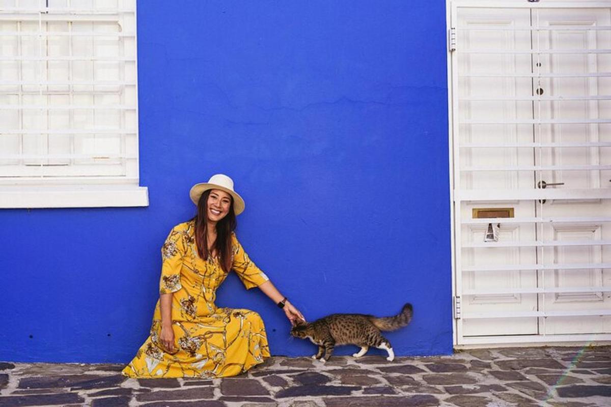 seorang wanita duduk di sebelah dinding biru dengan seekor kucing