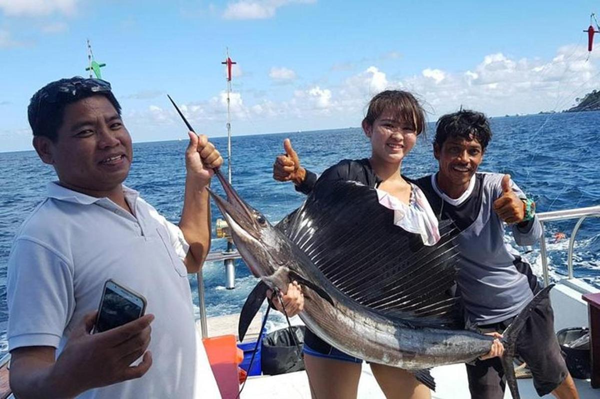 Tres personas sosteniendo un pez en una red en un barco