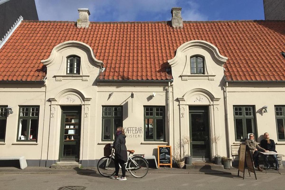 naine, kes jalutab jalgrattaga hoone ees