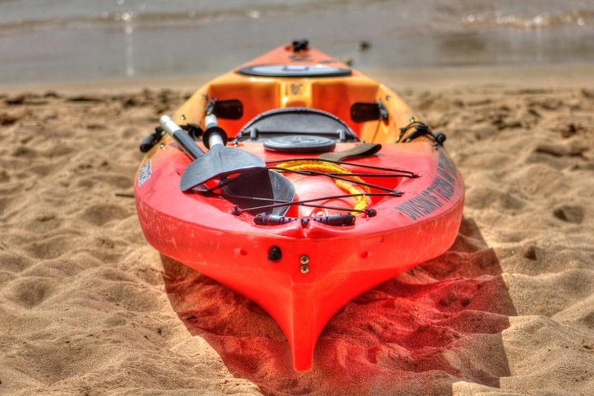 un kayak rosso appoggiato sulla sabbia di una spiaggia