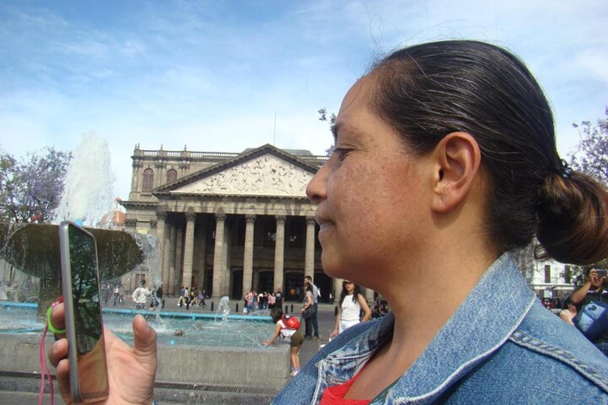ženska fotografira fontano pred stavbo