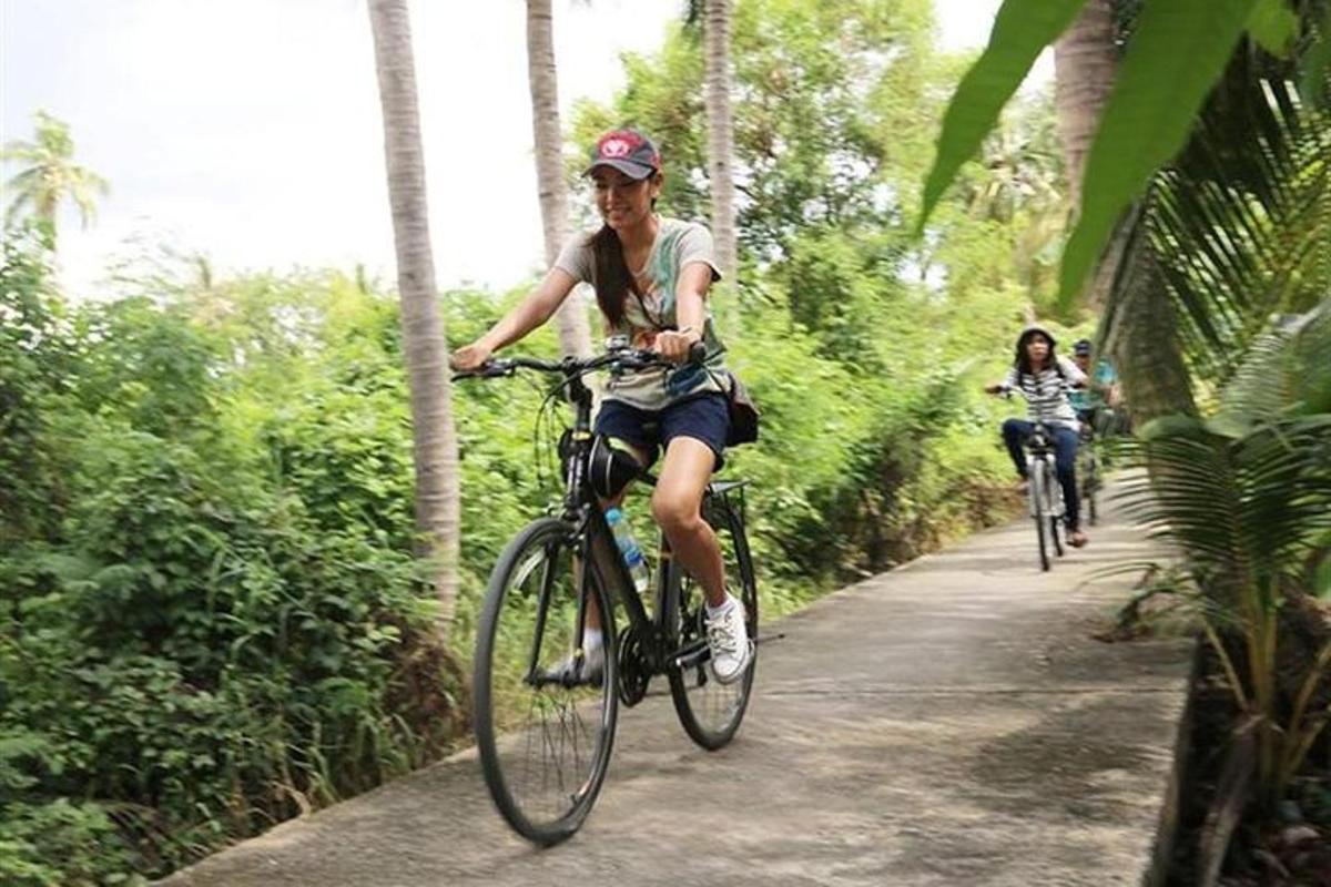 two people riding bikes down a path in the jungle