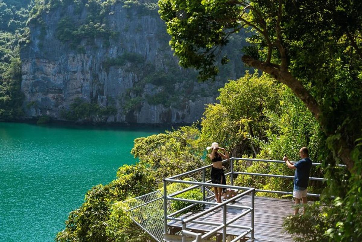 um grupo de pessoas em pé em um calçadão perto de um lago