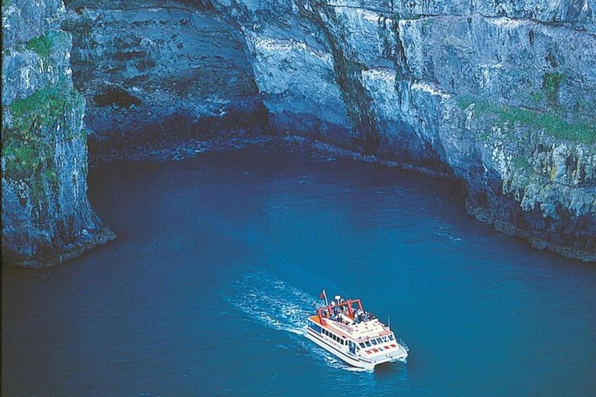 a boat in the water next to a cave