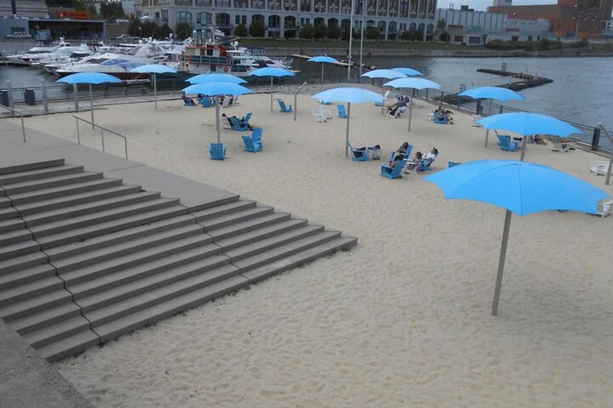 uma praia com guarda-sóis azuis e pessoas sentadas na areia