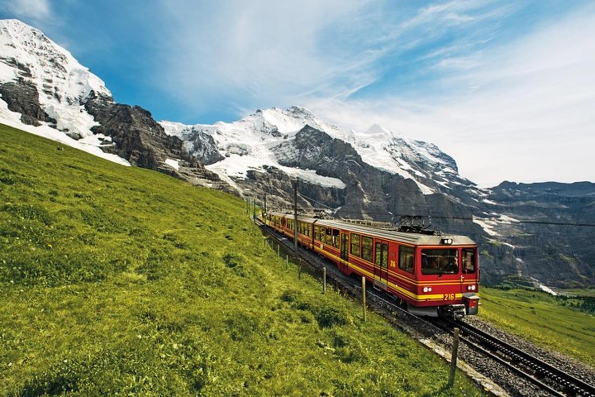 ein roter Zug auf den Gleisen in den Bergen