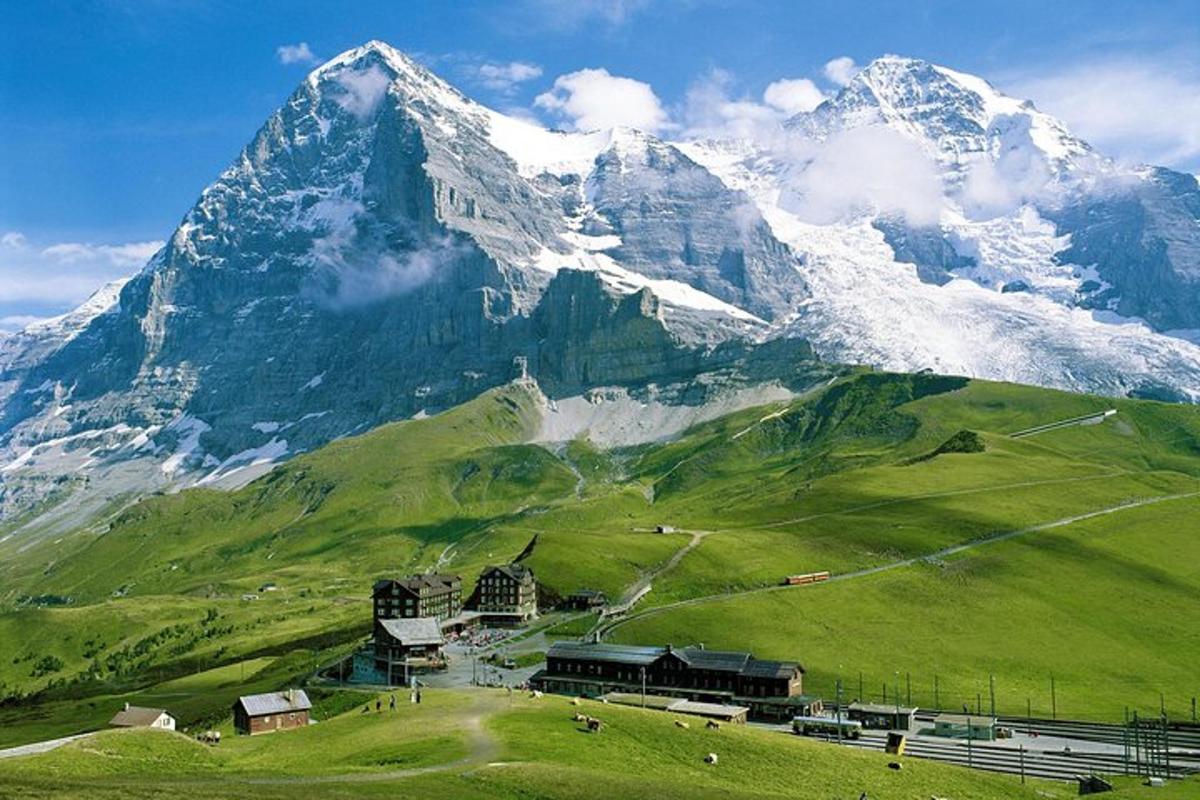 ein Berg mit einem grünen Feld und einem Gebäude davor