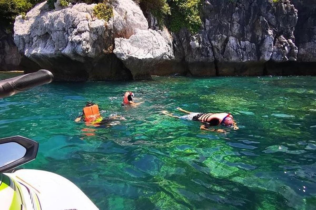tres personas en el agua junto a un barco