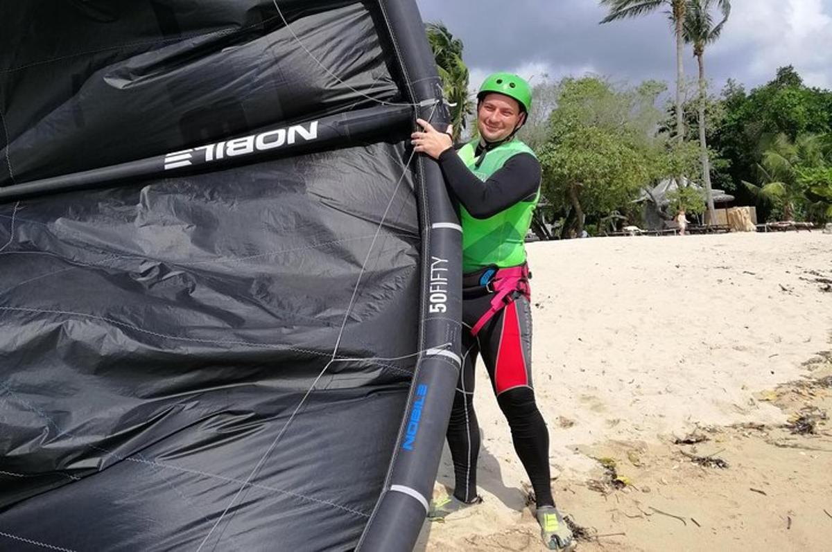 een vrouw staat naast een vlieger op het strand