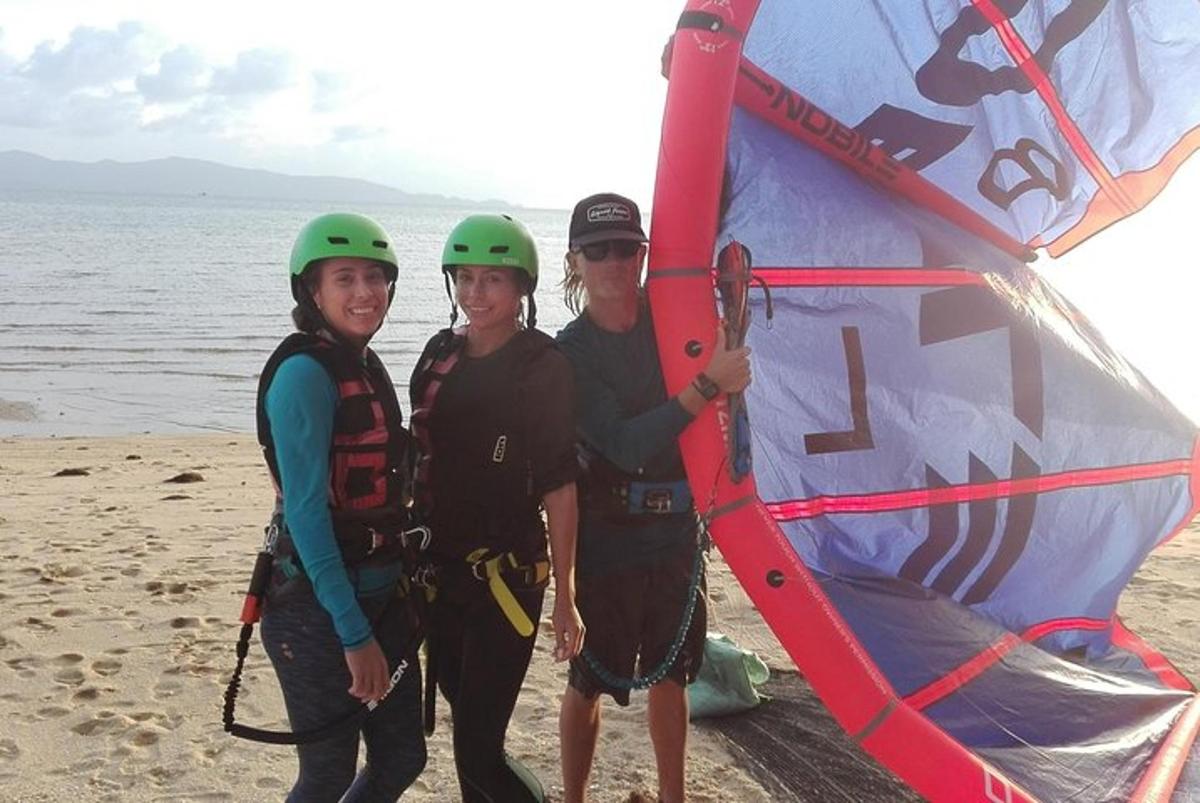 un gruppo di persone in piedi sulla spiaggia con un aquilone