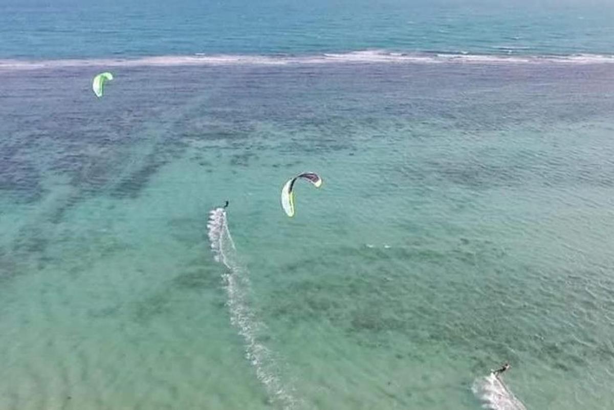 twee mensen vliegen vliegers in het water