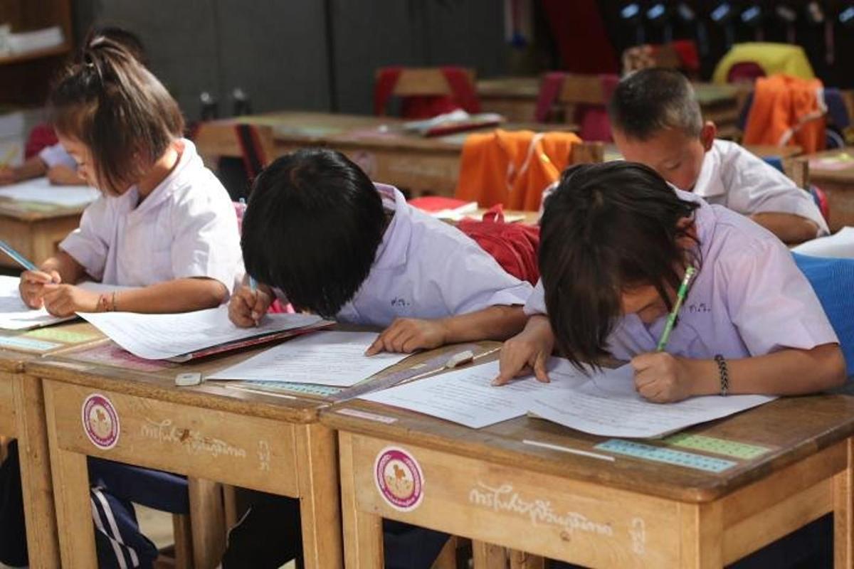 a group of children sitting at a table studying