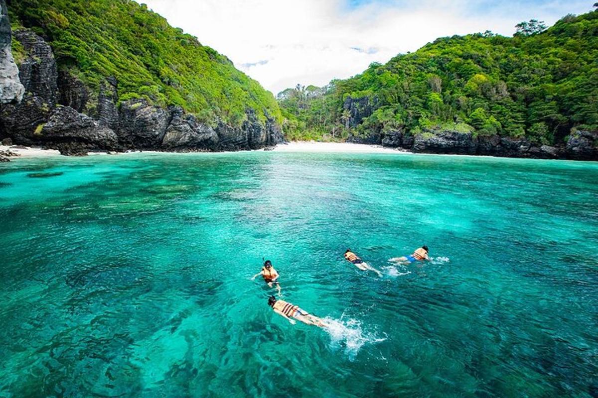 tiga orang berenang di dalam air berhampiran pantai