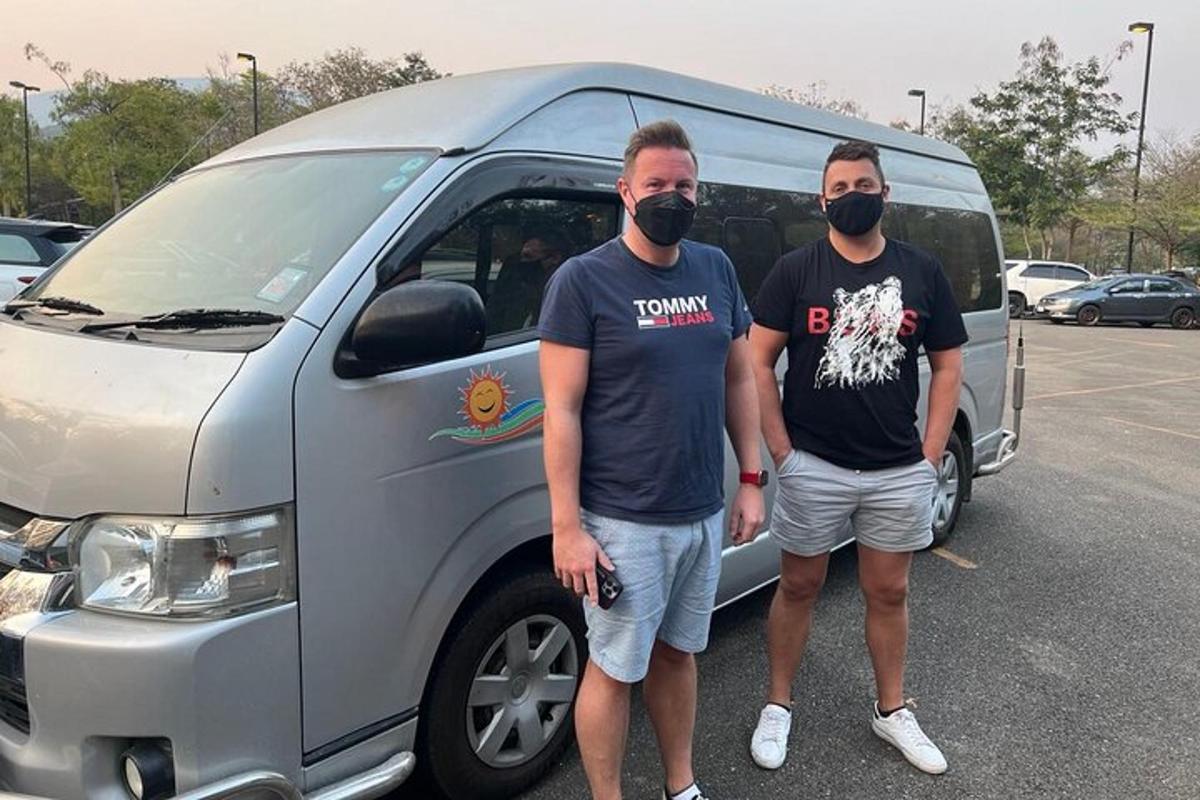 dois homens usando máscaras em pé na frente de uma van