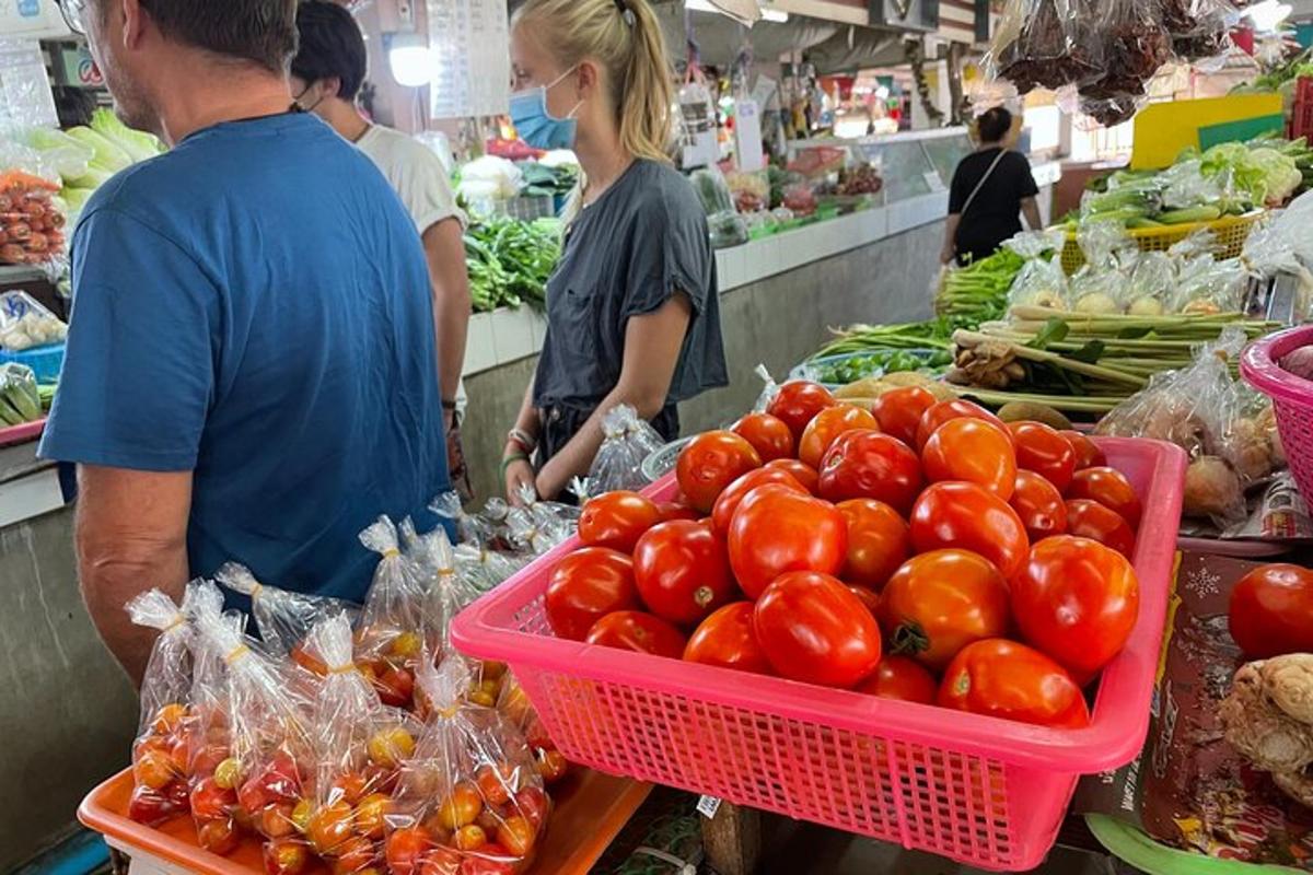 a man standing in a market with a basket of tomatoes