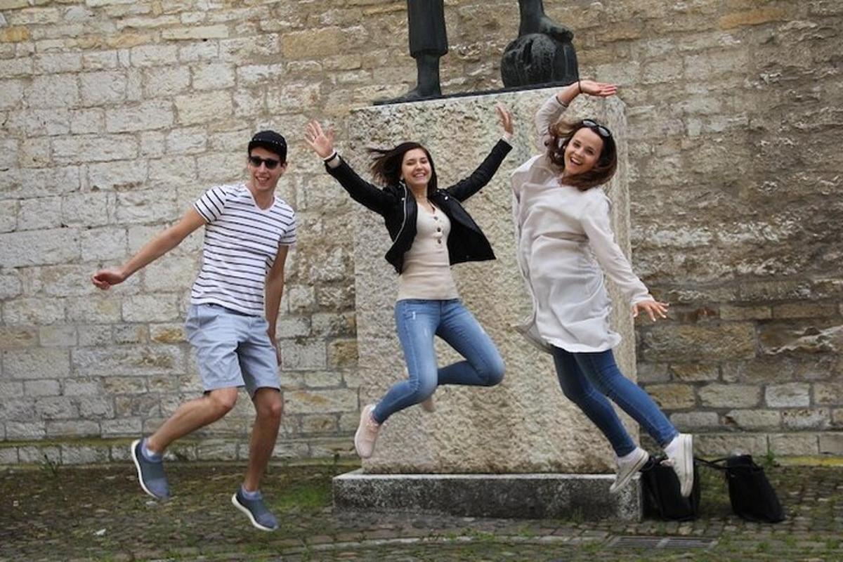 three young people jumping in front of a statue