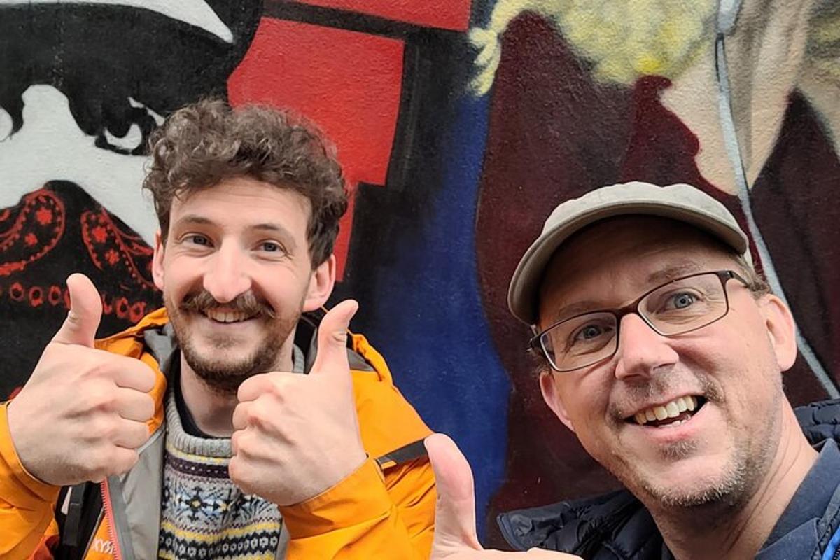 two men giving the thumbs up in front of a wall