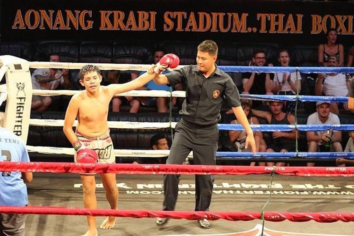 isang lalaking nakatayo sa harap ng isang boxing ring na may hawak na lalaki