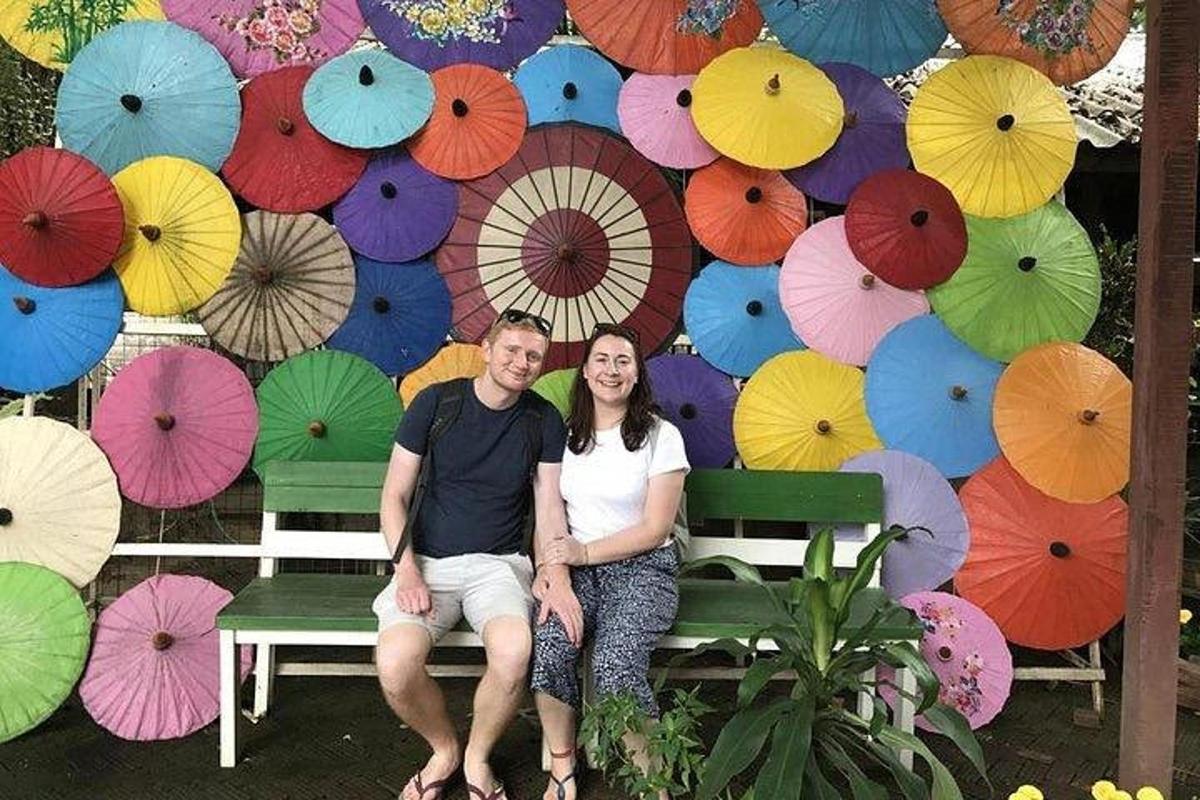 một người đàn ông và một người phụ nữ ngồi trên một chiếc ghế dài có ô